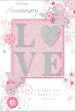 This anniversary card is a gentle celebration of enduring romance, composed in soft pastel pinks, misty greys, and silvery highlights that feel as intimate as a quiet dinner at home in Penge. At the centre of the design, the word "LOVE" is formed in raised, softly rounded letters dusted with fine glitter, inviting touch and catching the light with every small movement. The "O" is replaced by a shimmering heart textured in silver, giving the design a focal point that glows like a cherished keepsake. Surrounding this central motif, delicate blossoms in blush, mauve, and pale ivory open with a painterly, watercolour softness. Their outlines are refined and flowing, with slender stems and curling tendrils that suggest both care and lightness, echoing the artistry of an experienced florist composing a romantic anniversary bouquet. Tiny details-floating petals, looping swirls, and subtle butterflies-add a sense of motion, as if a soft spring breeze were drifting through a garden near Penge High Street. The background is a muted blush pink, evenly lit and unfussy, allowing the floral design and central heart to stand out. Elegant script reads "On Our Anniversary" and "I love you today and always," written in a calm, graceful style that complements rather than crowds the artwork. The layering of raised glitter, printed blooms, and smooth card stock creates a tactile richness that makes the piece feel special enough to keep. It looks like the kind of card chosen alongside a bouquet of pastel roses and lilies, ready for same-day local delivery to mark a shared journey with quiet, heartfelt sincerity.